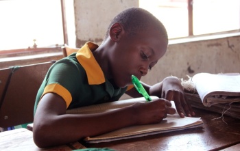 Un giovane bambino prende appunti in classe in una scuola in Zimbabwe.