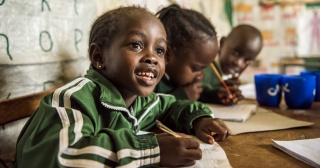 Un giovane bambino prende appunti con entusiasmo in classe.