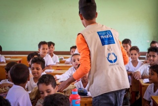 Un volontario consegna forniture di aiuto a una scuola.